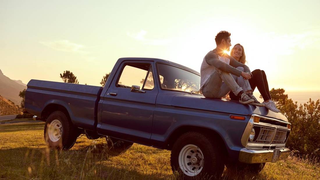 couple sitting on car hood